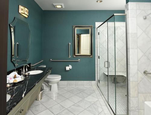 a bathroom with a toilet and a glass shower at Woolley's Classic Suites in Aurora