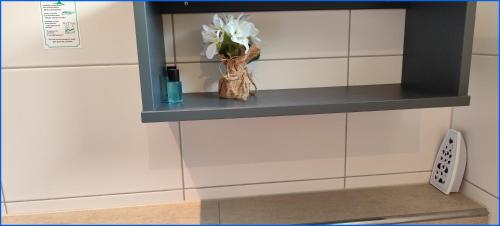a shelf with a vase of flowers on a wall at Sport Arena HOTEL Waldshut in Waldshut-Tiengen