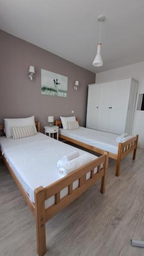 two beds in a room with white walls and wooden floors at Double Room, Shared bathroom- Rooms GEA in Prizren