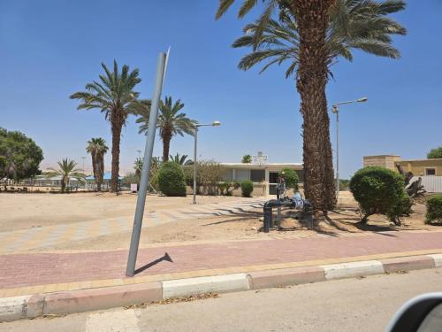 a pole on a sidewalk next to palm trees at Zimmer Belev HaKikar- Dead sea in Neʼot HaKikar