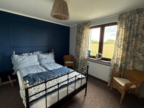 a blue bedroom with a bed and a window at Domek nad jeziorem in Kikół