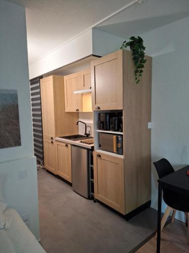 a kitchen with wooden cabinets and a stove top oven at Appartement neuf proche Nantes avec parking in Carquefou