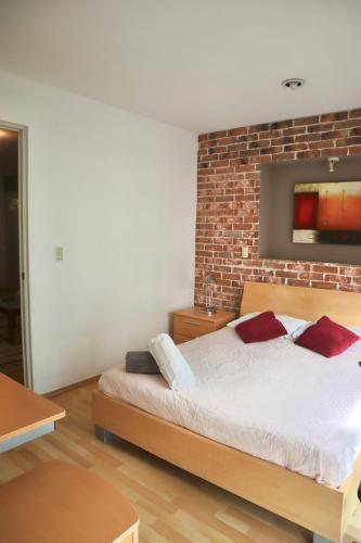 a bedroom with a bed and a brick wall at Departamento Arquimedes 214 - 503 in Mexico City