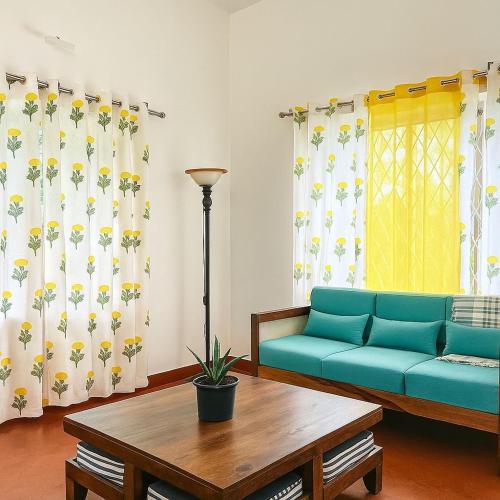 a living room with a blue couch and a table at MyYearlyStay in Udupi - Colonial in Udupi