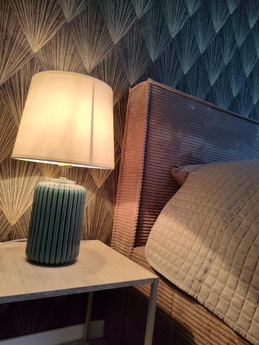 a bedroom with a bed and a table with a lamp at UrbanHome Rokiškis in Rokiškis