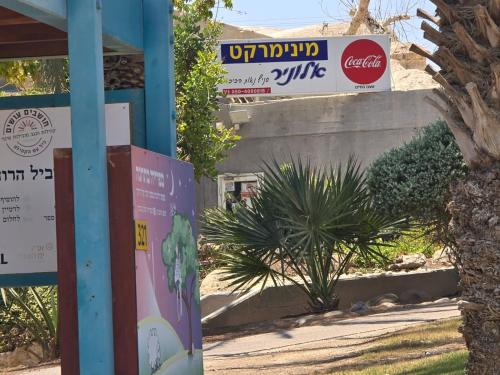 a sign on a pole in front of a building at Zimmer Belev HaKikar- Dead sea in Neʼot HaKikar