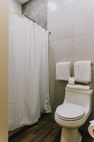 a bathroom with a white shower curtain and a toilet at Hospedaje Consular by Dunas in Ciudad Juárez