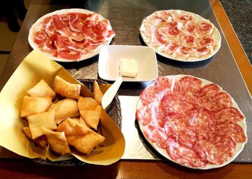 a table with three pizzas and chips and cheese at HOTEL BELVEDERE in Rivalta di Brentino