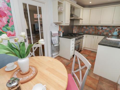 a kitchen with a table with a vase of flowers on it at Rose Briar Cottage in Morpeth