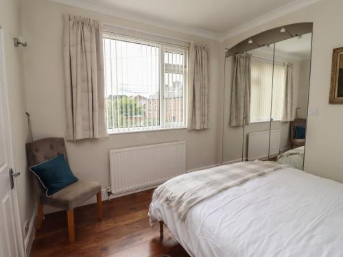 a bedroom with a bed and a mirror and a chair at Rose Briar Cottage in Morpeth