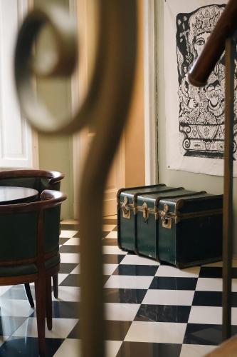 a green suitcase sitting on a black and white checkered floor at Santuzza Art Hotel Catania in Catania