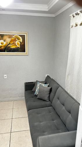 a gray couch in a living room with a painting at 10 MIN AEROPORTO GUARULHOS in Guarulhos