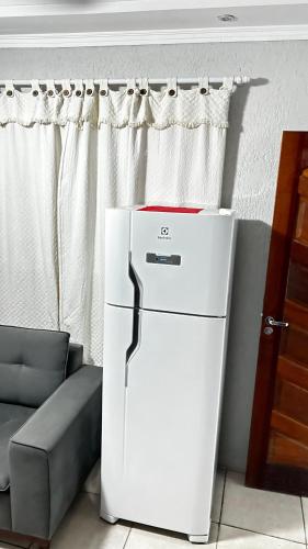 a white refrigerator in a living room next to a couch at 10 MIN AEROPORTO GUARULHOS in Guarulhos