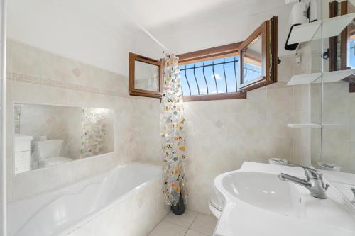 une salle de bain blanche avec une baignoire et un lavabo dans l'établissement La Maison de Noélie - RDJ, à Le Bar-sur-Loup