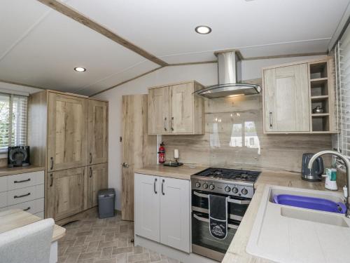 a kitchen with wooden cabinets and a stove top oven at Winscales Rest in Workington