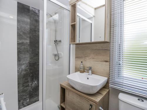a bathroom with a white sink and a shower at Winscales Rest in Workington
