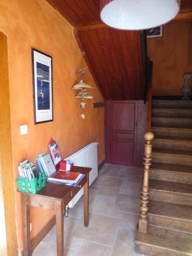 a room with a table and stairs with a red door at Gite Les Arrebourits 4 étoiles in Anères