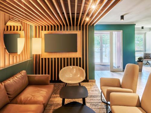 un salon avec un canapé et une télévision à écran plat dans l'établissement B&B HOTEL Frankfurt-Niederrad, à Francfort-sur-le-Main