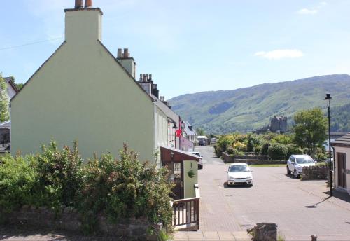 a green building with a car parked on a street at Eilean Donan View in Dornie