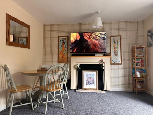 a living room with a table and a tv above a fireplace at 3 Bed Entire House - Runcorn in Runcorn