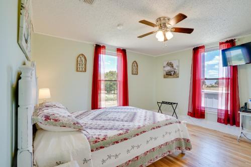 a bedroom with a bed with red curtains and a ceiling fan at Decatur Farmhouse Getaway with Deck and Backyard in Decatur