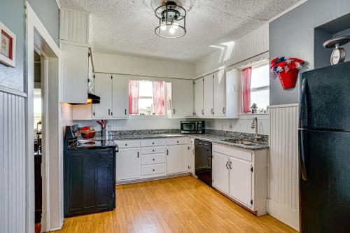 a kitchen with white cabinets and a black refrigerator at Decatur Farmhouse Getaway with Deck and Backyard in Decatur