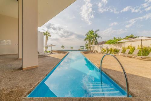 a swimming pool in a villa with blue water at Departamento con vista lateral al mar en Zantamar in Cruz de Huanacaxtle