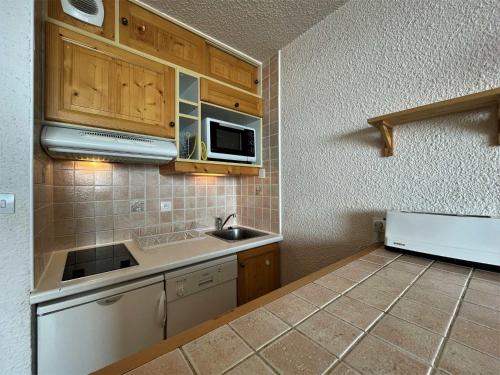 une petite cuisine avec un évier et un micro-ondes dans l'établissement Appartement rénové 8 pers, pied des pistes, Les Menuires, balcon sud, services dispo - FR-1-452-171, aux Menuires