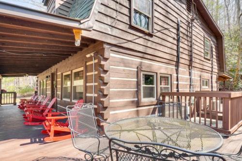a wooden cabin with a table and chairs on a deck at Bear In Flannel Cabin Hot Tub in Townsend