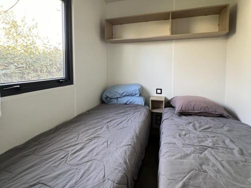 two beds in a small room with a window at MobilHomeTorreilles in Torreilles