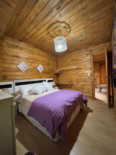 a bedroom with a bed in a wooden cabin at Cabaña Luz de Luna en La Esmeralda Rocha in La Esmeralda 