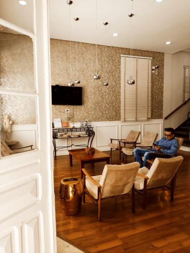 a man sitting in a chair in a living room at MOVA Hotel D'oeste - Localizado em frente a Praça Principal da Cidade, na área Central - Pé na Praça in Poços de Caldas