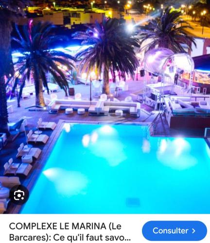 - une piscine avec des chaises et des palmiers la nuit dans l'établissement Coquet T 2 Le barcares Mer, au Barcarès