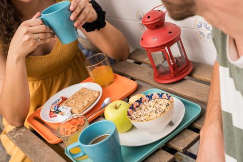 eine Gruppe von Menschen, die an einem Tisch mit Frühstückslebensmittel sitzen in der Unterkunft La Pimentera Rooms in Córdoba