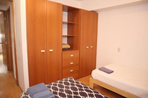 a bedroom with a wooden cabinet and a bed at Hermoso depto c/alberca y gym Polanco in Mexico City