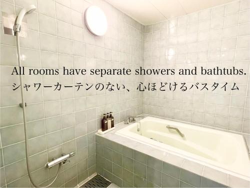 a bathroom with a bath tub and writing on the wall at Hotel Ritz Koshien in Nishinomiya