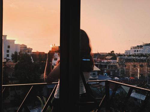 a woman taking a picture of the city from a window at Angkor Legacy Boutique in Siem Reap