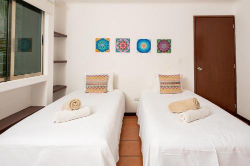 two beds in a room with white sheets and towels at Apartamento amplio en zona ideal a 5min de WALLMART in Cancún