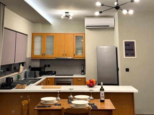eine Küche mit Holzschränken und einem Tisch mit einer Flasche Wein in der Unterkunft Cecilia Sea View Apartment in Kardamena, Kos in Kardamaina