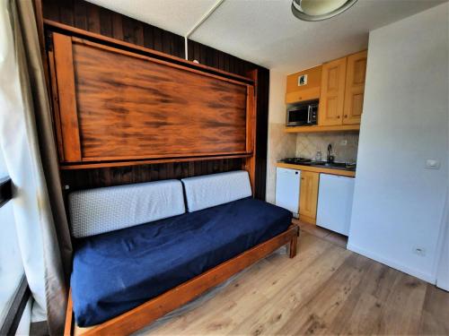 Ce lit se trouve dans une petite chambre dotée d'un mur en bois. dans l'établissement Résidence Genepi - Studio 3 personnes ski aux pieds aux Ménuires MAE-5914, aux Menuires