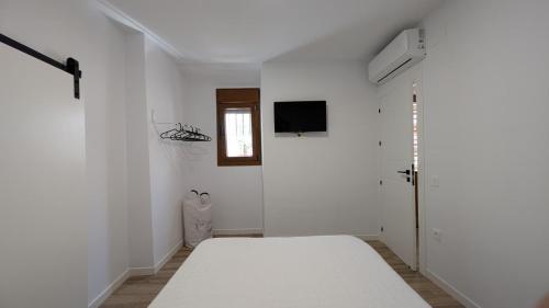 a white room with a bed and a television at El Descanso de Baba Yaga in Soportújar