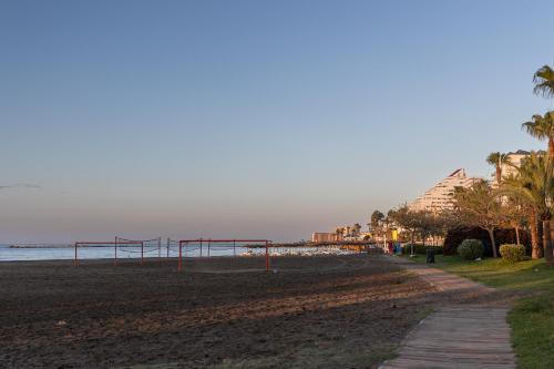 a beach with a volleyball court and the ocean at Hotel Marina Benalmádena in Benalmádena