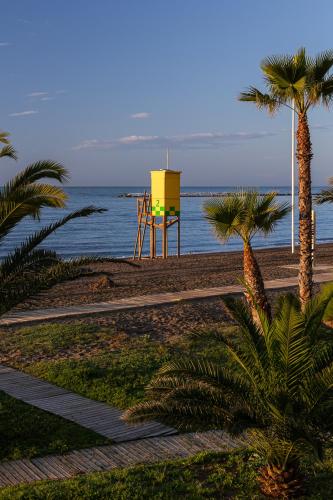 a lifeguard tower on a beach with palm trees and the ocean at Hotel Marina Benalmádena in Benalmádena