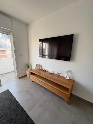 a living room with a flat screen tv on a wall at Boutique apartment in Rishon LeẔiyyon