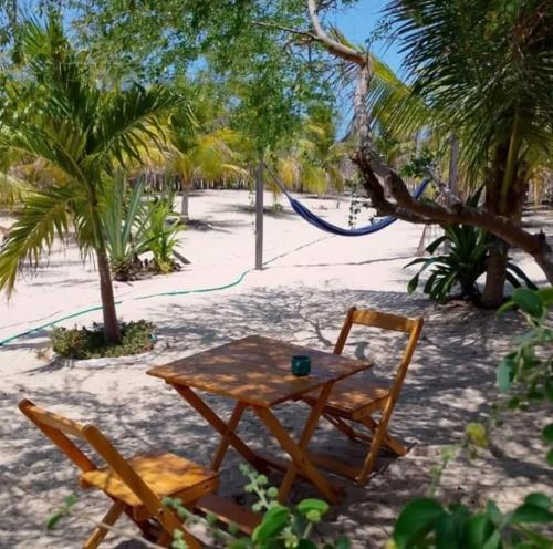a table and chairs on the beach with a hammock at Barefoot KiteHouse in Luis Correia