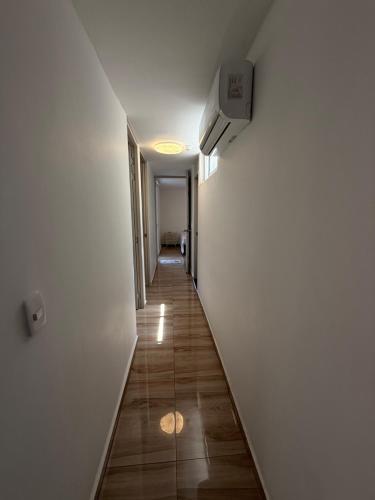 a long hallway with a white wall and wooden floors at Apartamento Turistico Bosaso in Villavicencio