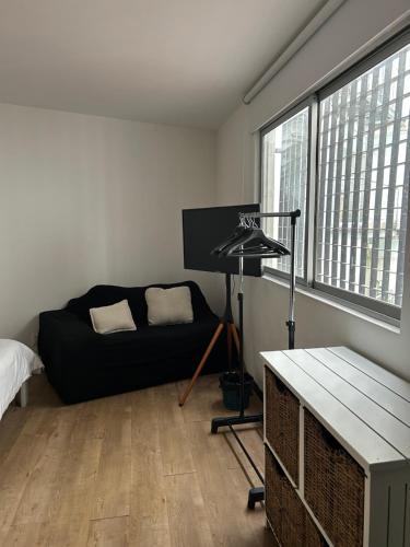 a living room with a black couch and a table at Linda Habitación Privada Polanco 2 camas Mat y baño in Mexico City