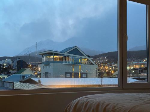 a bedroom with a view of a building from a window at Austral Apartamentos in Ushuaia