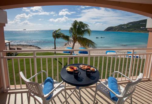 a table and chairs on a balcony with the beach at Divi Little Bay Beach Resort in Philipsburg