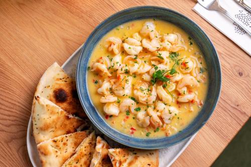 a bowl of shrimp soup with pita bread on a table at Armonia by Aristocratis in Tîrgu Neamţ